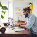 Person with beard and headphones works on a laptop.